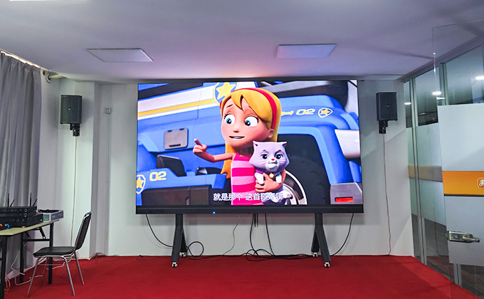 In a meeting room, a large LED display (led screen) shows an animated scene. With audio speakers and simple set - up, it highlights the led display\'s role in indoor visual presentations.