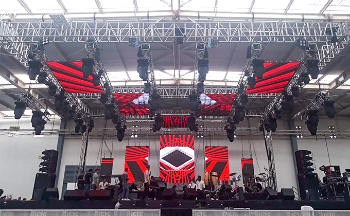 A concert touring setup features multiple LED screens (led display) with striking red patterns. Equipped with stage lighting and sound systems, it showcases the led screen\'s role in creating immersive live music visuals.